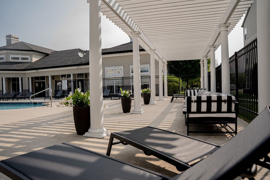 A patio with a black and white striped chair and a pool in the background.at 92West, West Des Moines, IA 50266  