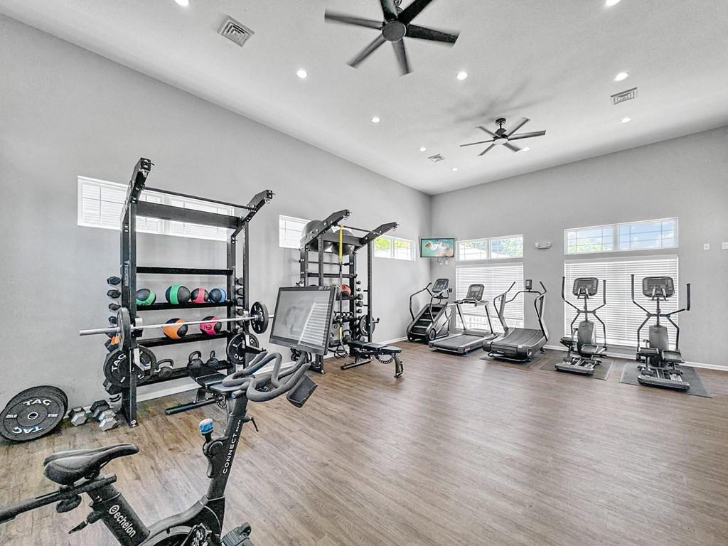 a gym with cardio machines and weights on a wooden floor at 92West, West Des Moines, IA 50266  