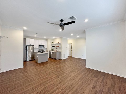 A kitchen with a refrigerator, microwave, and oven is visible from the living room.