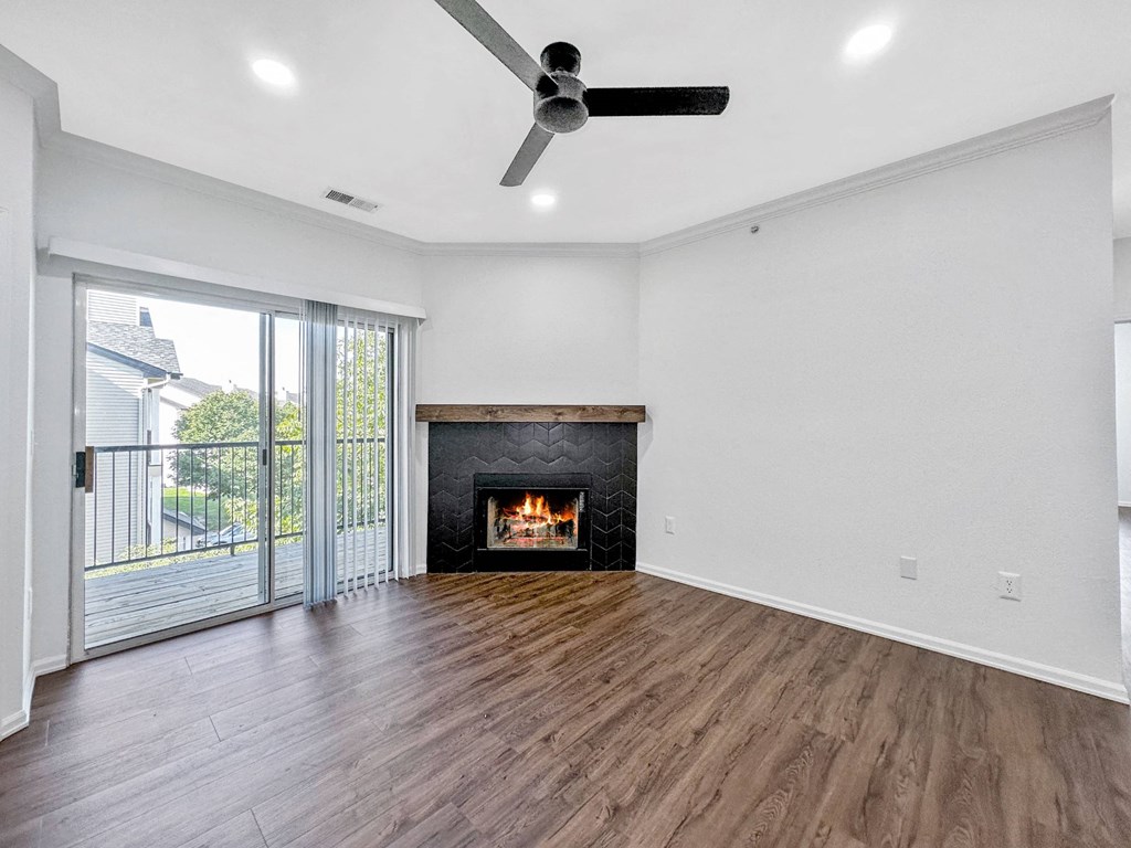 an empty living room with a fireplace and a sliding glass door at 92West, West Des Moines Iowa  