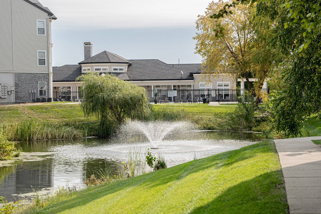 a pond with a fountain in front of a building at 92West, West Des Moines  