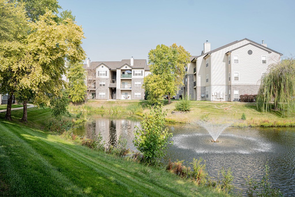 a fountain in the pond with an apartment building in the background at 92West, West Des Moines, IA 50266