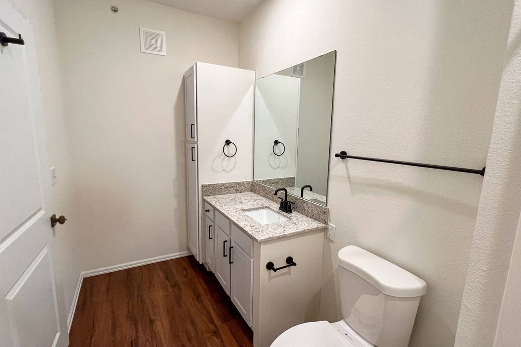 a bathroom with a toilet and a sink and a mirror at 92West, West Des Moines, IA  