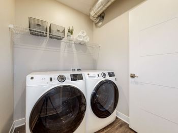 Two white front load washing machines in a laundry room.at Linc, Des Moines  