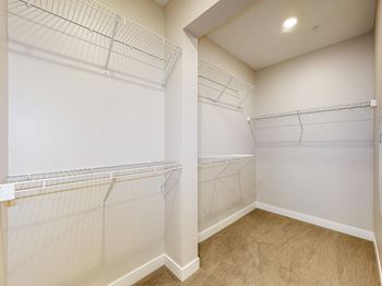A walk-in closet with white shelving and a tan carpet.at Linc, Des Moines, 50309  