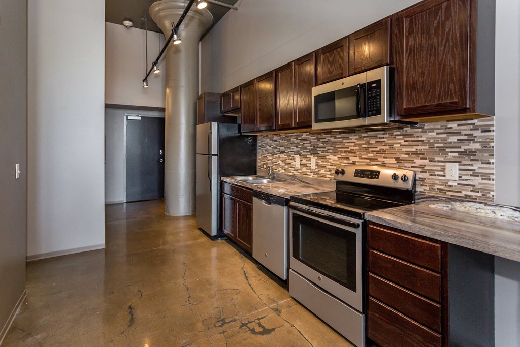 Kitchen with stainless steel appliances and wooden cabinets at Ballyard Lofts, Iowa