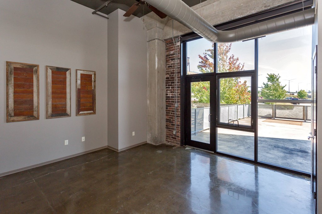 Living room with a large window and a door to a patio at Ballyard Lofts, Iowa , 50309
