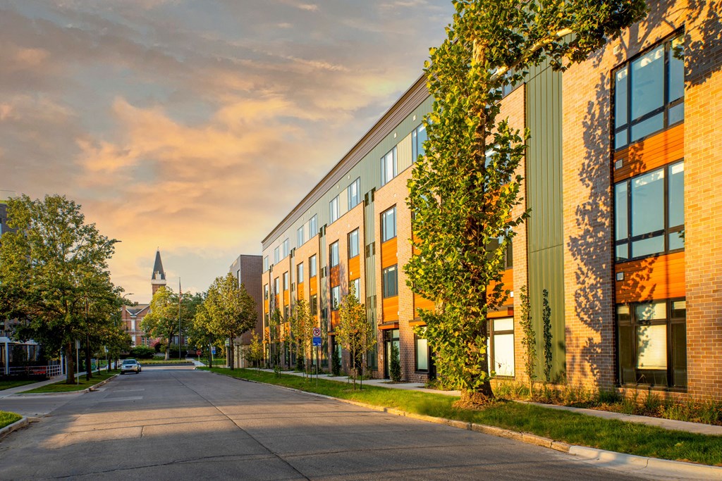 a city street with a brick building and a church in the distance at Canary Lofts, Des Moines, 50311