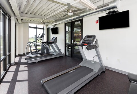 A gym with treadmills and a television mounted on the wall. at Eagle View Lofts, Iowa