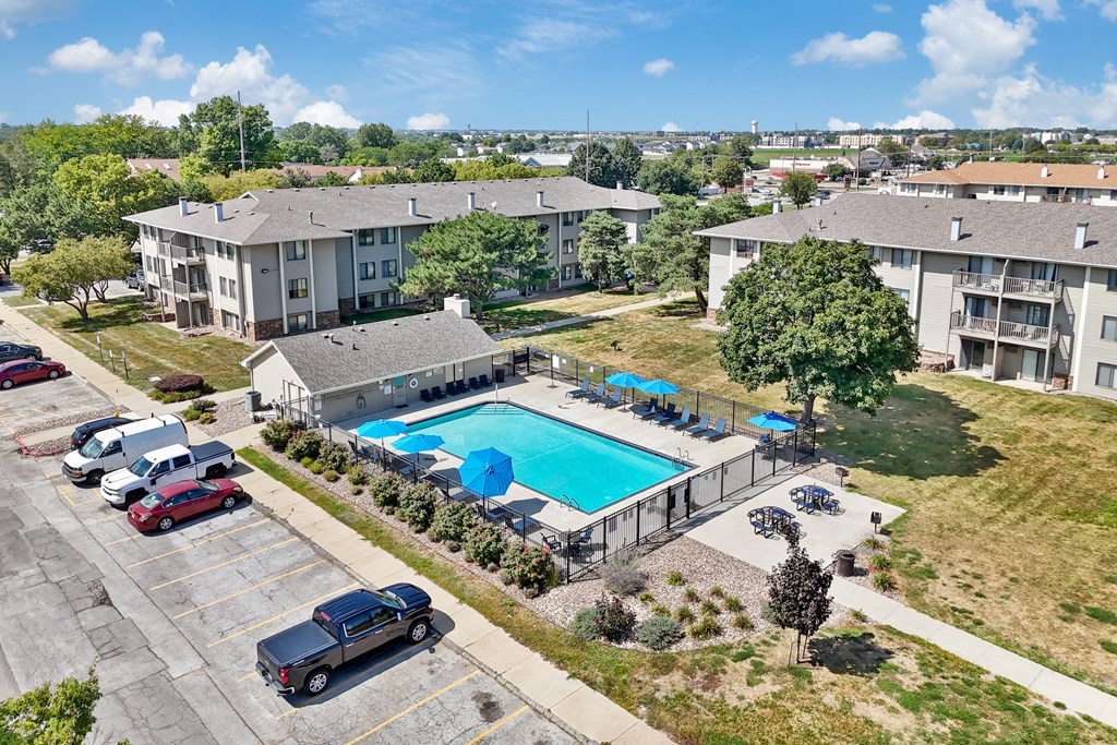 A swimming pool surrounded by apartment buildings and cars.