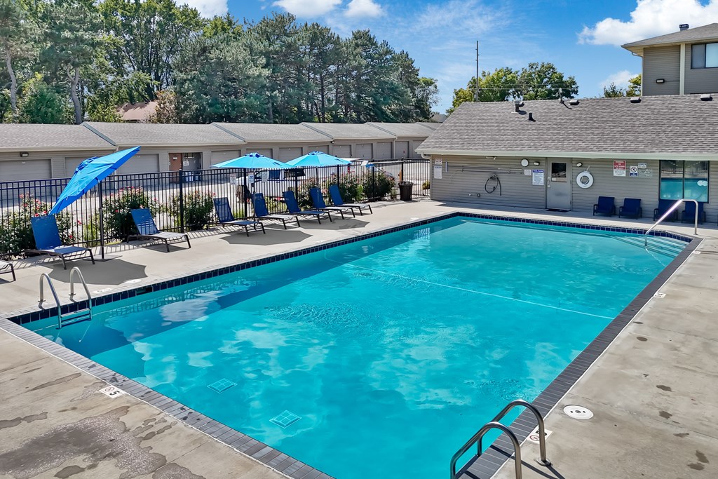 A large swimming pool with a diving board and lounge chairs.