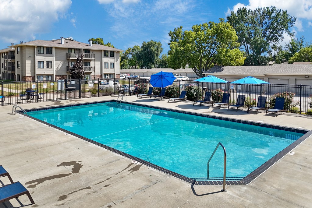 A swimming pool surrounded by chairs and umbrellas.