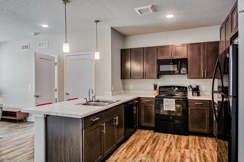 A kitchen with dark wood cabinets and a black refrigerator.