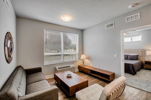 A living room with a couch, chair, and a table with a lamp on it.