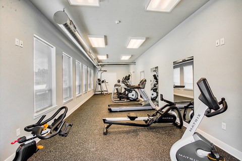 A gym with a variety of equipment including treadmills, stationary bikes, and rowing machines.