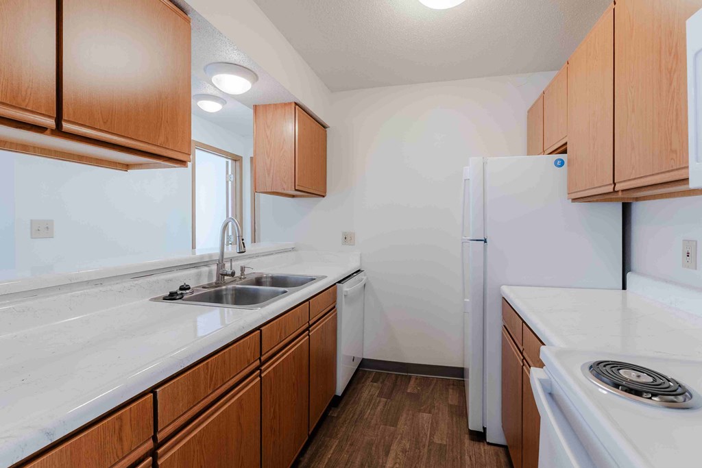 A kitchen with white appliances and wooden cabinets.