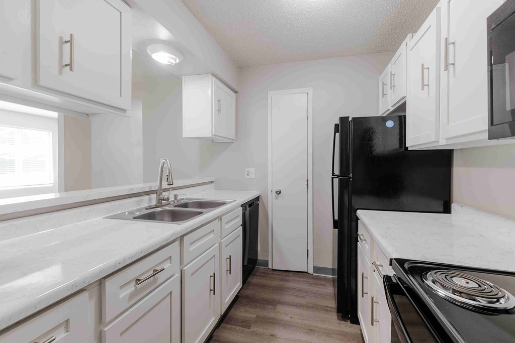 A kitchen with black appliances and white cabinets.