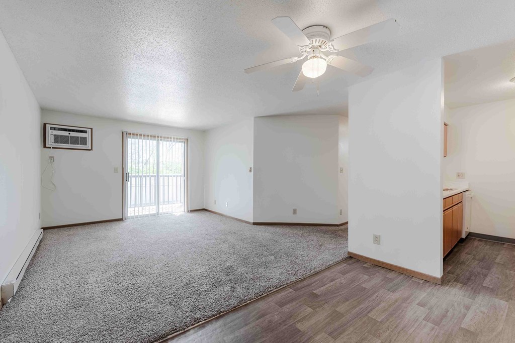 A spacious room with a ceiling fan and a window with blinds.
