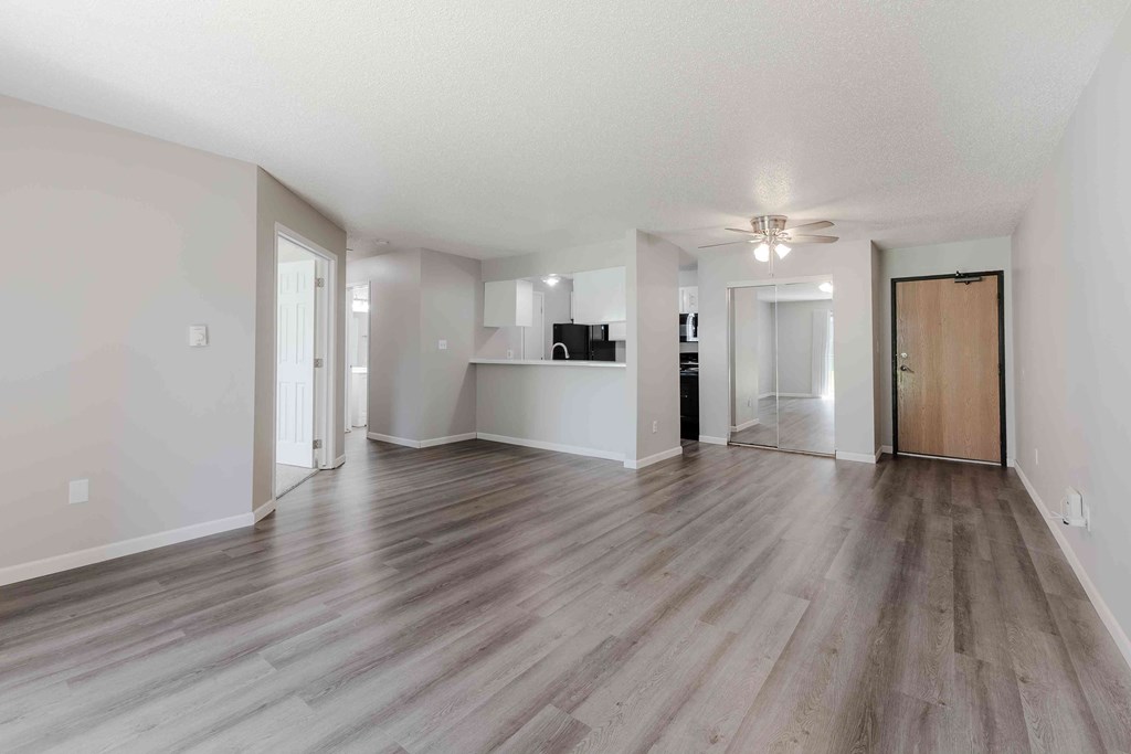 A spacious room with wooden flooring and a ceiling fan.