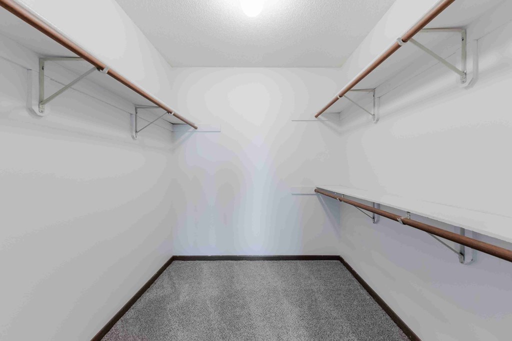 A long, narrow hallway with a grey carpeted floor and white walls.