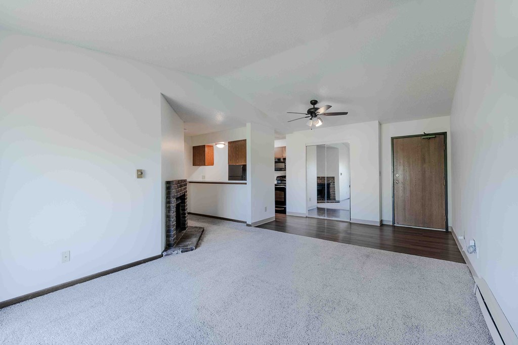 A spacious living room with a fireplace and a ceiling fan.