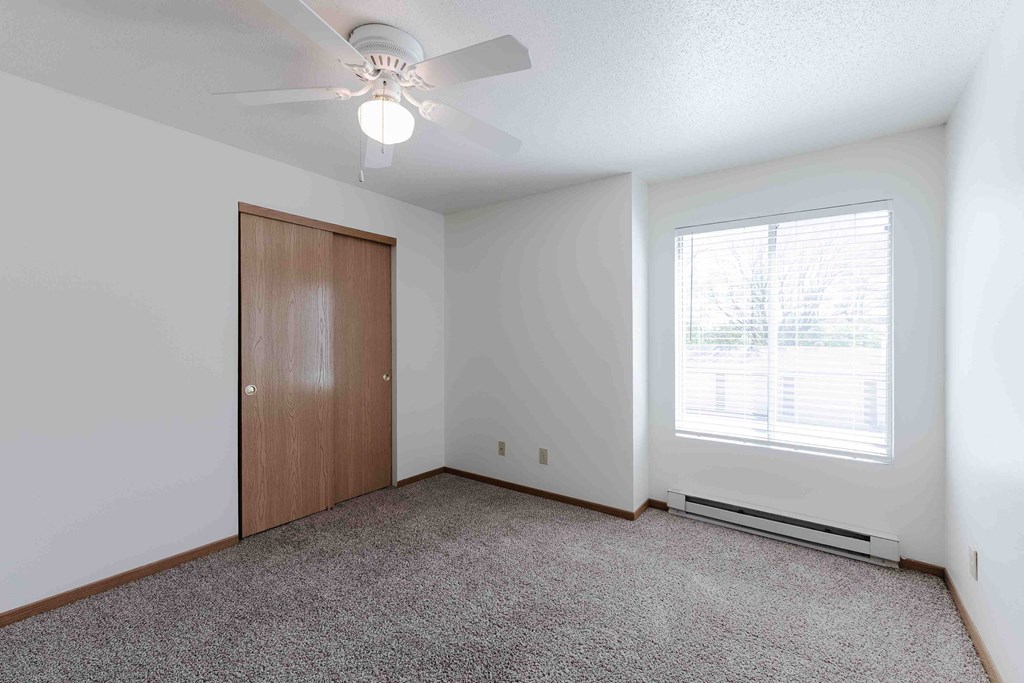 A room with a ceiling fan and a window with blinds.