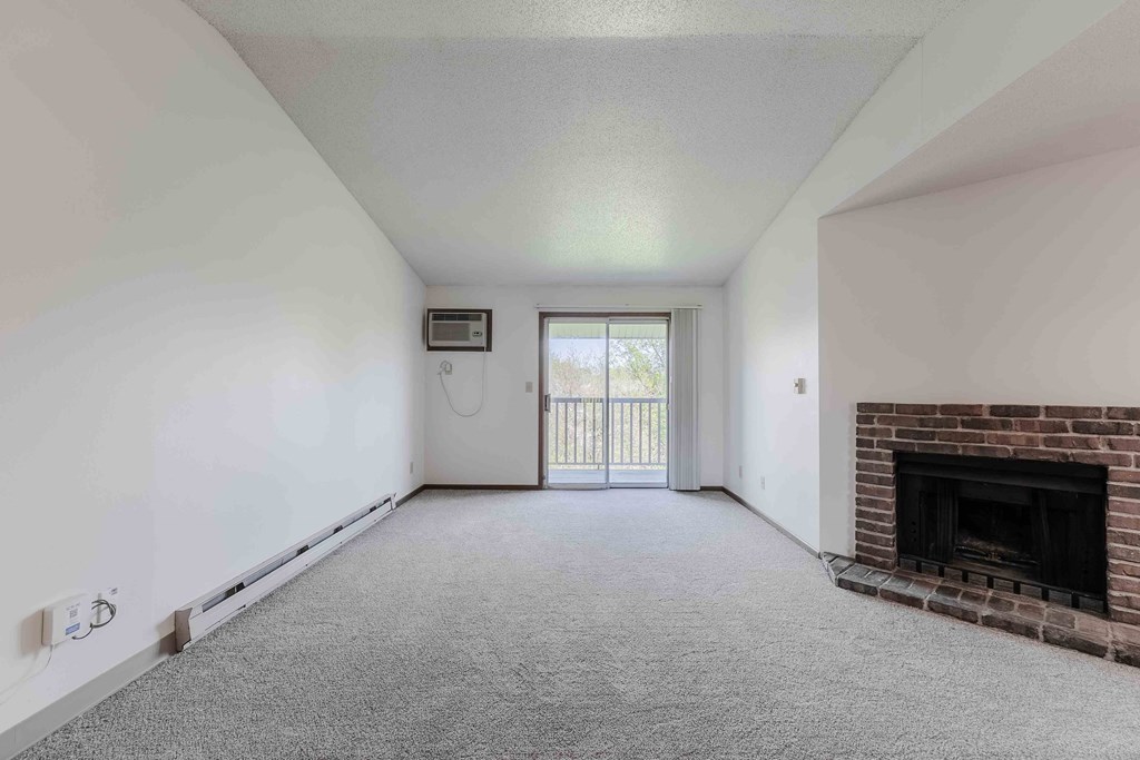 A room with a fireplace and a window with a view of a balcony.