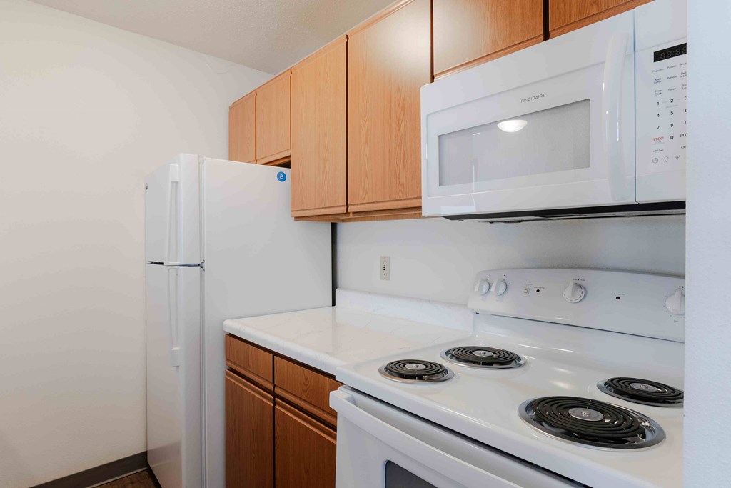 A white microwave oven is mounted above a white stove in a kitchen.