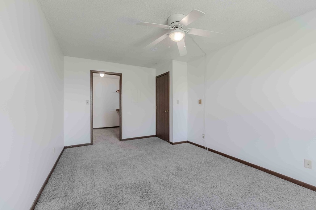 A room with a ceiling fan and carpeted floor.