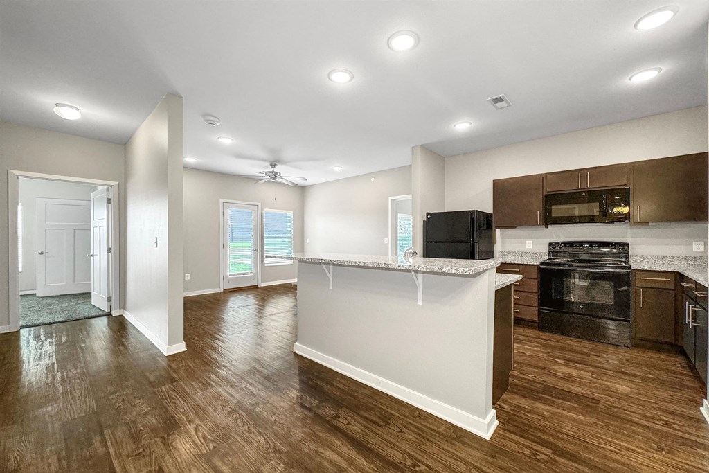 an open kitchen and living room with a kitchen island and wood flooring at The Barclay Apartments, Altoona, IOWA