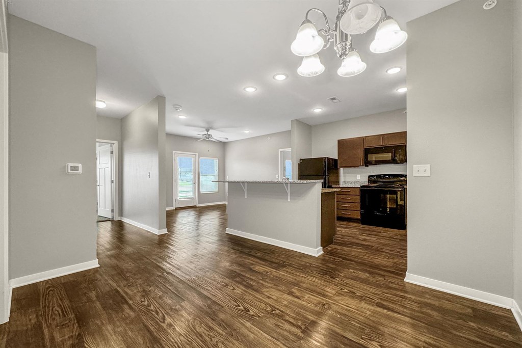 A spacious kitchen and living room with wood flooring and modern appliances. at The Barclay Apartments, IOWA, 50009