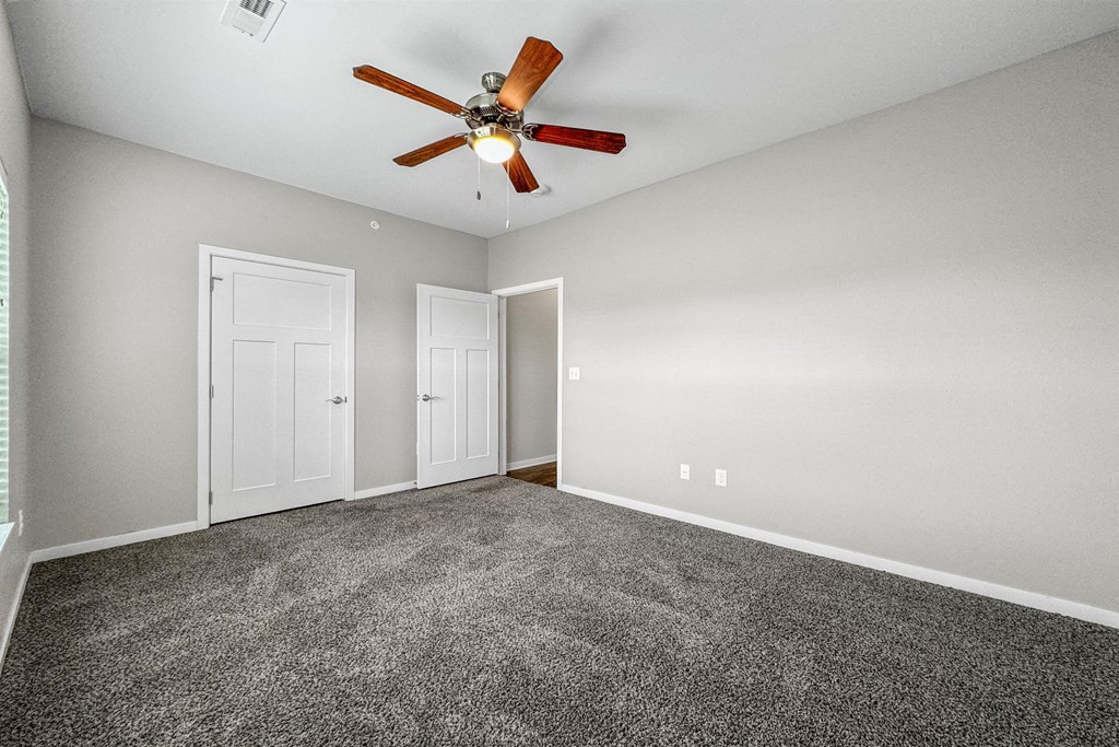an empty room with carpet and a ceiling fan at The Barclay Apartments, Altoona