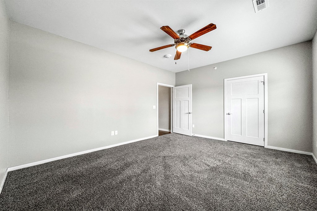 an empty room with carpet and a ceiling fan at The Barclay Apartments, Altoona, IA, 50009