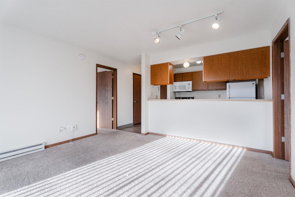 A spacious living room with a kitchen area in the background. at Rosemont Place Apartments, Des Moines, IA, 50320