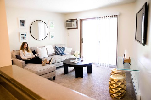 A woman is sitting on a couch in a living room.