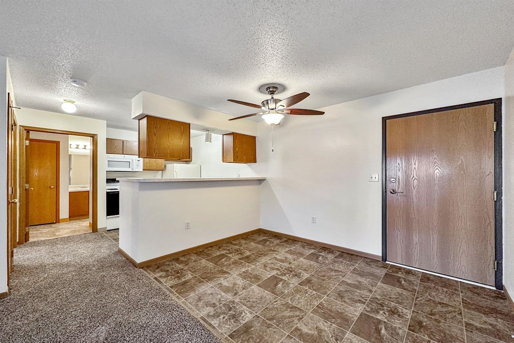 an empty living room with a kitchen and a ceiling fan at Somerset Apartments, Iowa, 50315