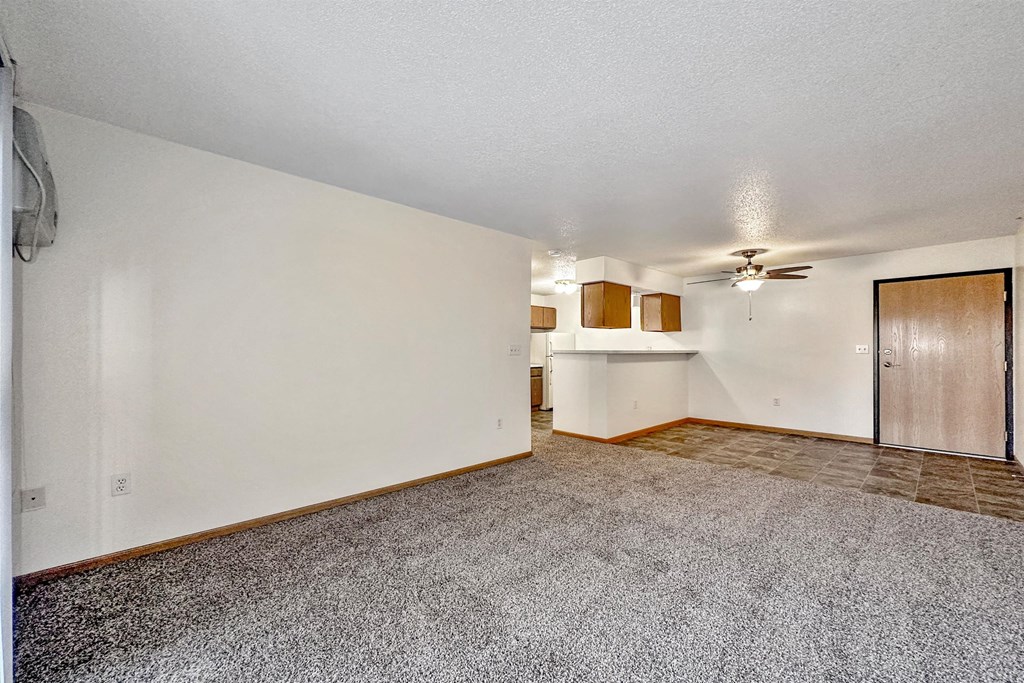 A spacious room with a ceiling fan and a door on the right side at Somerset Apartments, Des Moines, IA