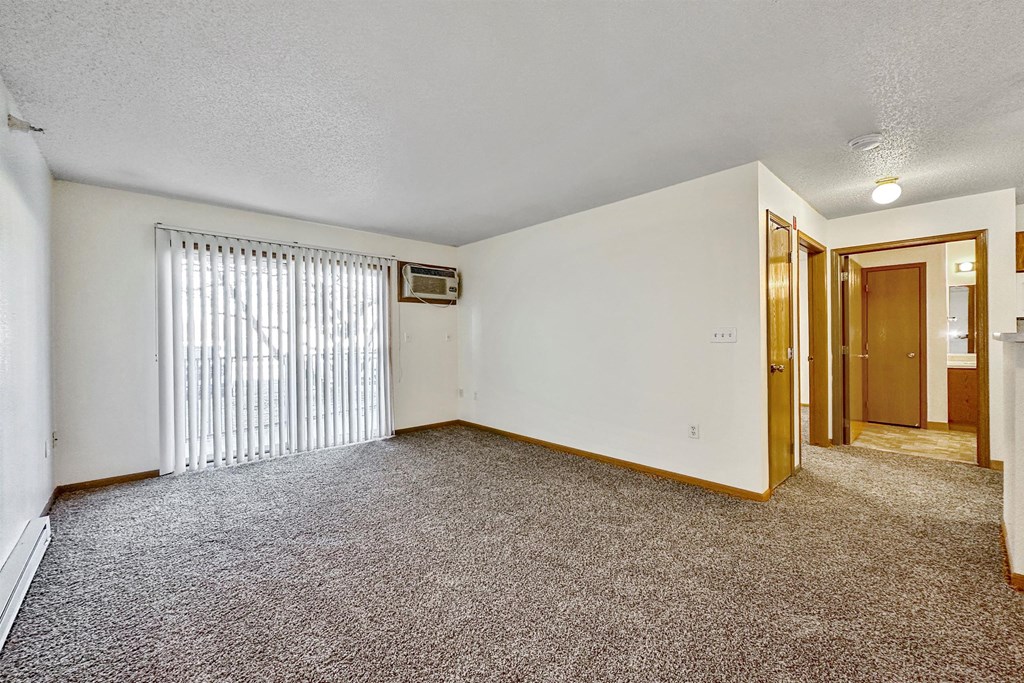 A room with a carpeted floor and a window with blinds at Somerset Apartments, Des Moines, 50315