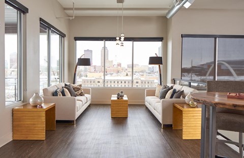 A modern living room with white furniture and a view of the city.