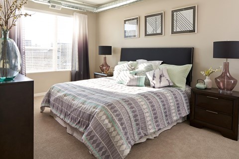 a bedroom with a bed and a dresser and a window at Velocity Apartments, Iowa