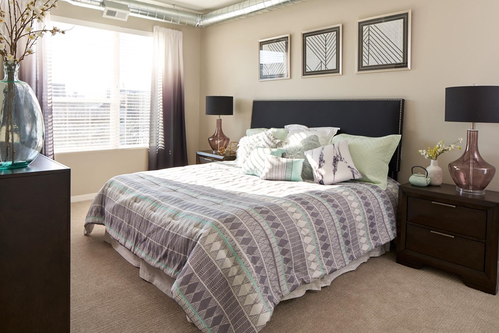 a bedroom with a bed and a dresser and a window a bedroom with a bed and a dresser and a window at Velocity Apartments, Iowa