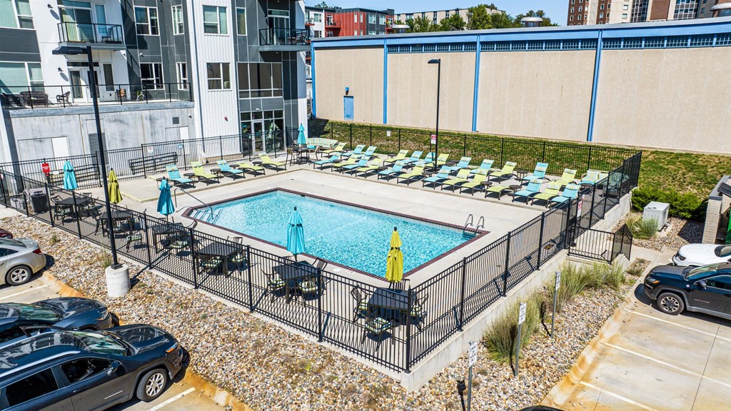 a swimming pool with lounge chairs in front of a building a swimming pool with lounge chairs in front of a building at Velocity Apartments, Des Moines, IA