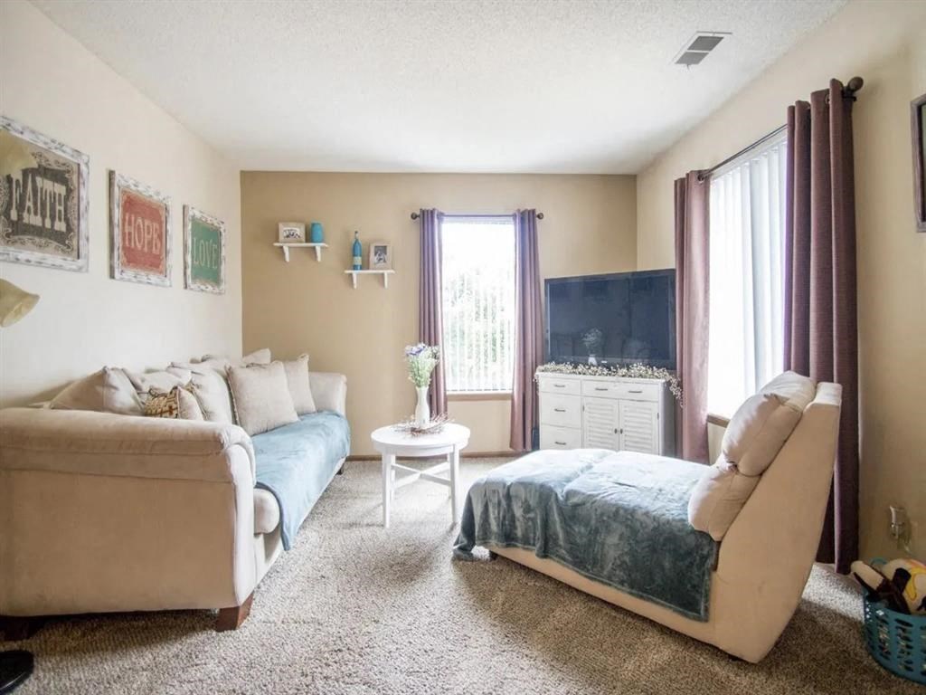 A living room with a couch, chair, and a small table. A living room with a couch, chair, and a small table at Hunters Run Apartments, Iowa, 50208