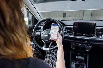a woman holding a cell phone in a car at Rialto Townhomes Apartments, Waukee, Iowa