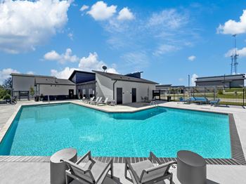 a swimming pool with chairs and a building in the background at Rialto Townhomes Apartments, Waukee, IA, 50263