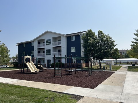 A playground area in front of a blue and white apartment building.