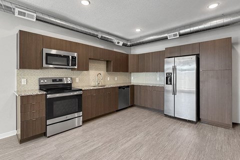A kitchen with brown cabinets and a stainless steel refrigerator.