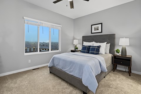 A bedroom with a bed, nightstand, and window.