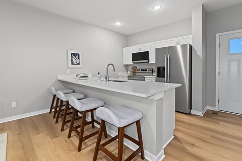 A kitchen with white countertops and a refrigerator.