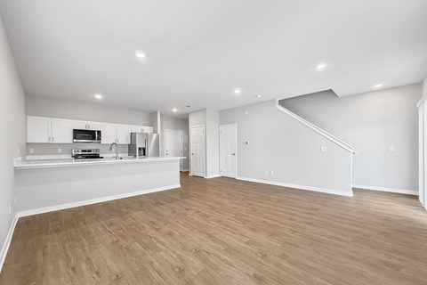 A spacious, empty room with wooden flooring and white walls.